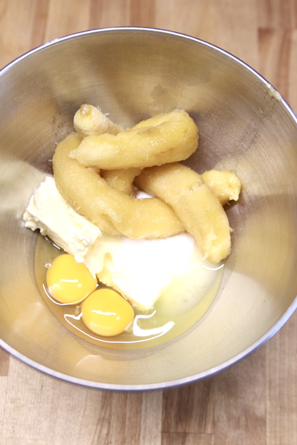 mixer bowl with bananas, sugar, eggs and butter