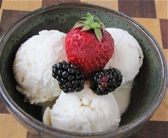 Bowl of vanilla ice cream with strawberry and blackberries.
