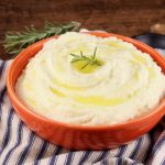 Bowl of mashed potatoes with melted butter and rosemary