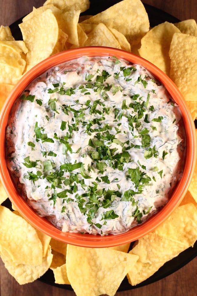 Knorr Spinach Dip in an orange bowl surrounded by tortilla chips