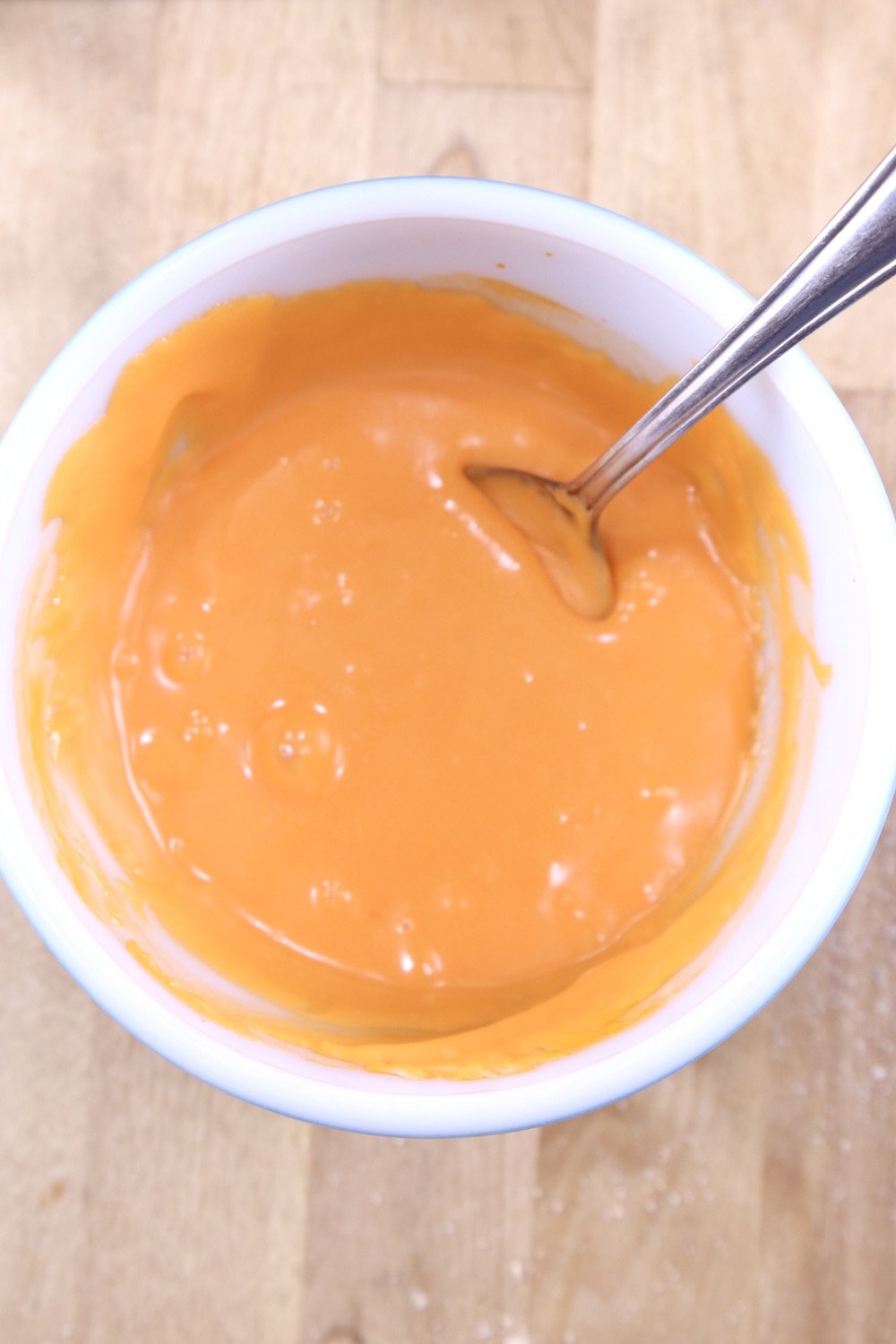 small bowl of orange fudge with a spoon