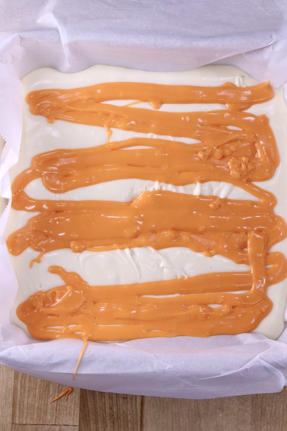 Pan of vanilla fudge with orange fudge drizzled over it