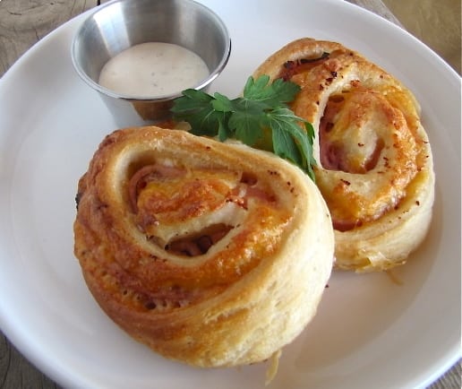 two ham and cheese roll ups with ranch on the side.