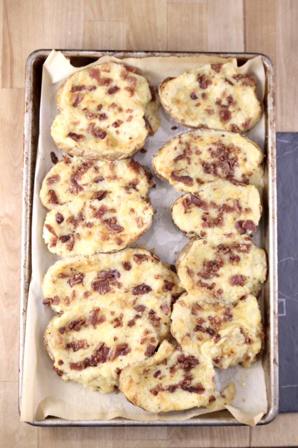 sheet pan of twice baked potato halves topped with bacon