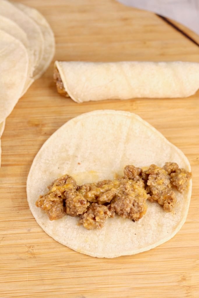 Filling tortillas with cheesy ground beef for taquitos
