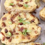 Twice Baked Potatoes on a baking sheet topped with bacon & green onions