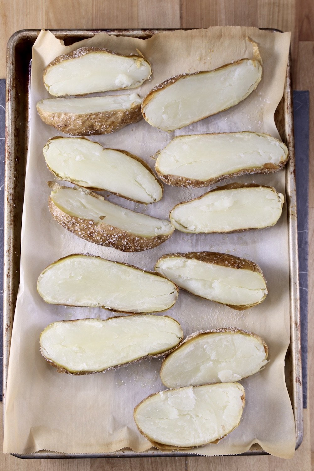baked potatoes sliced in half on a baking sheet