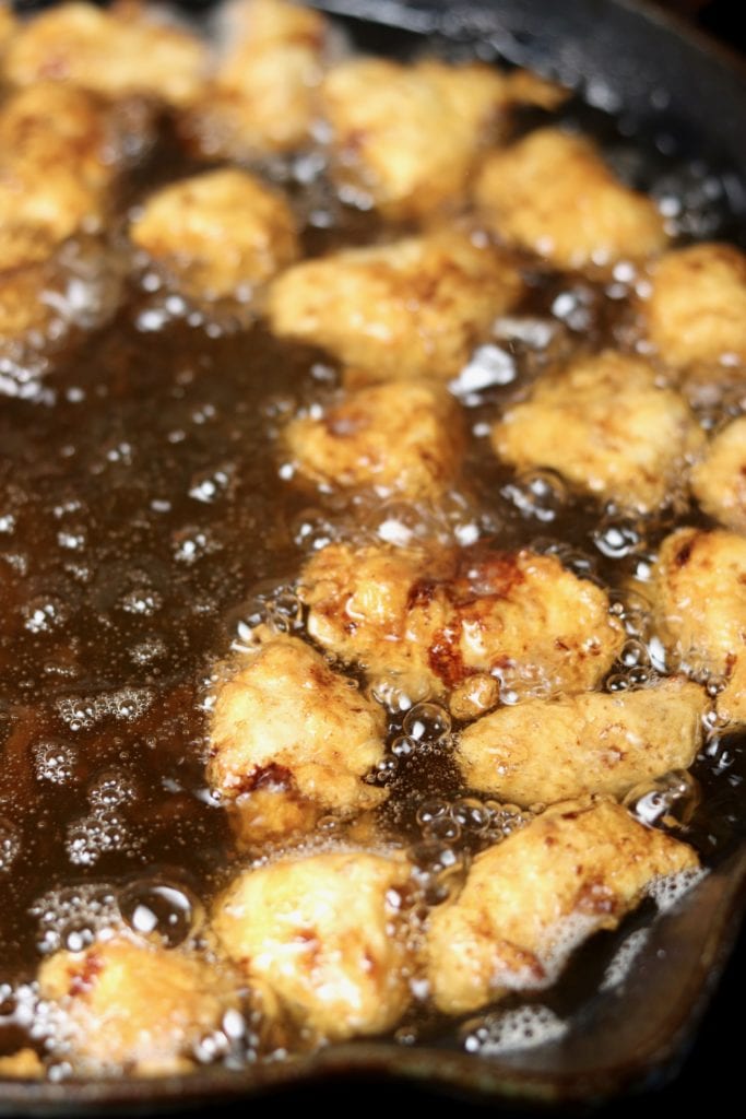 Frying chicken pieces in a skillet of oil