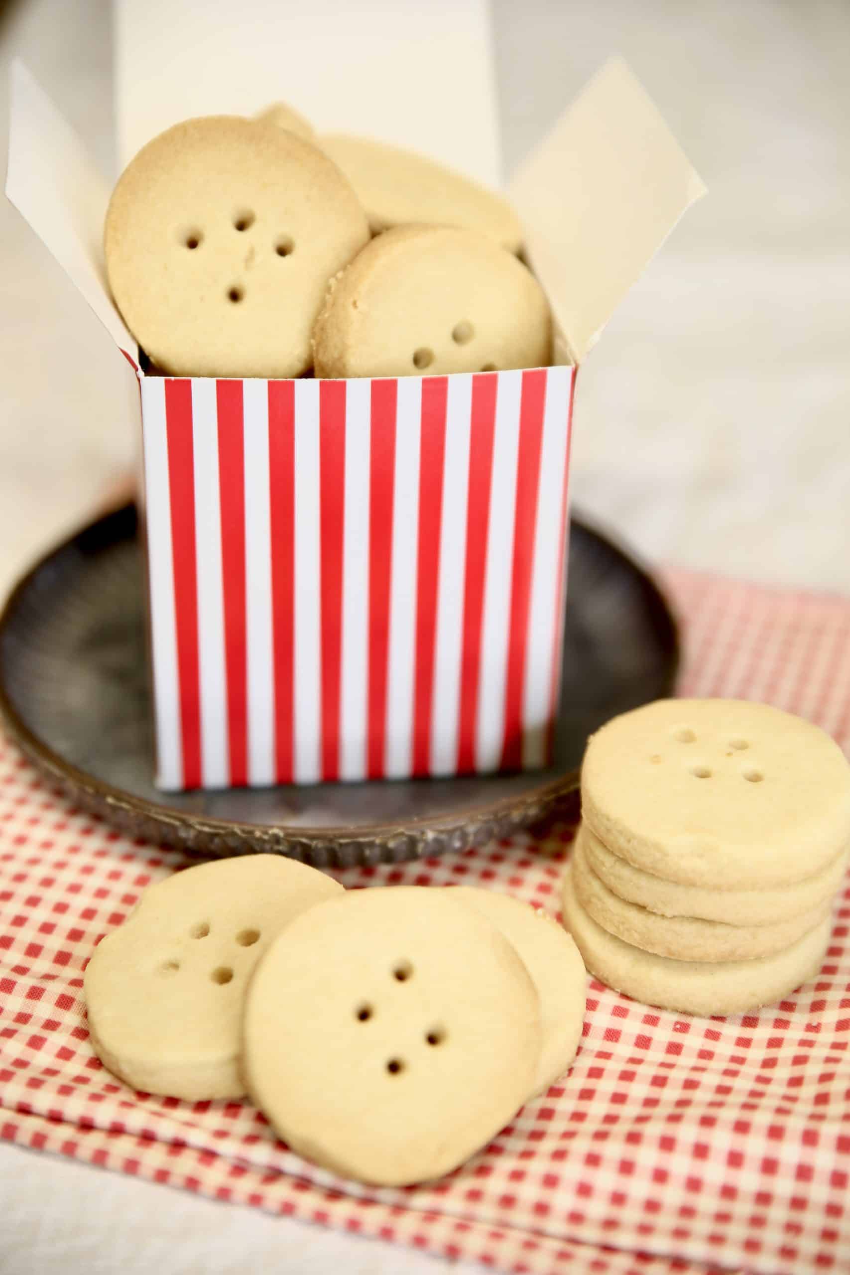 Box of shortbread cookies with cookies on a gingham napkin.