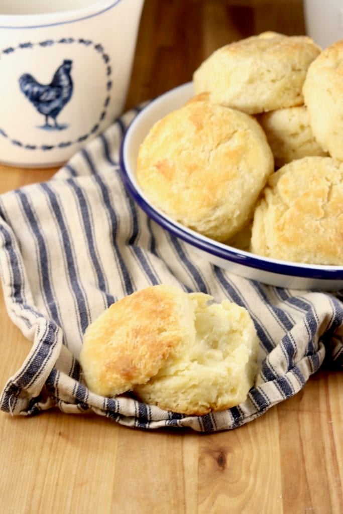 Biscuit with butter and tray of biscuits