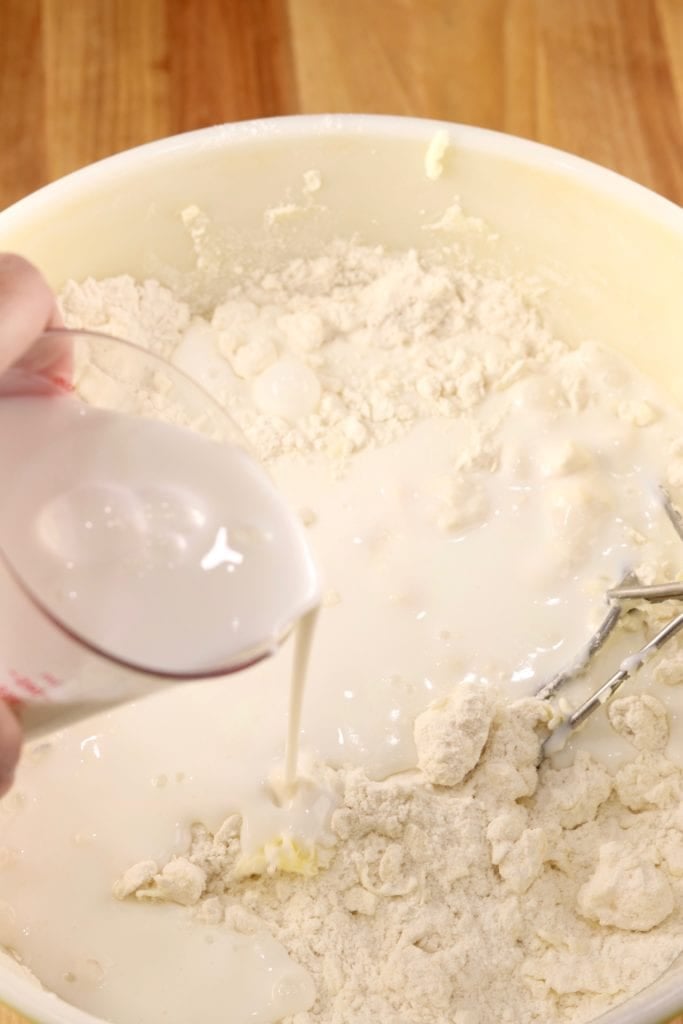 pouring buttermilk into biscuit dough