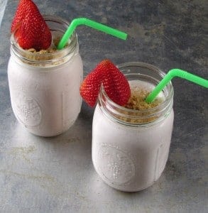 2 glass jars with strawberry ice cream garnished with strawberry and green straw