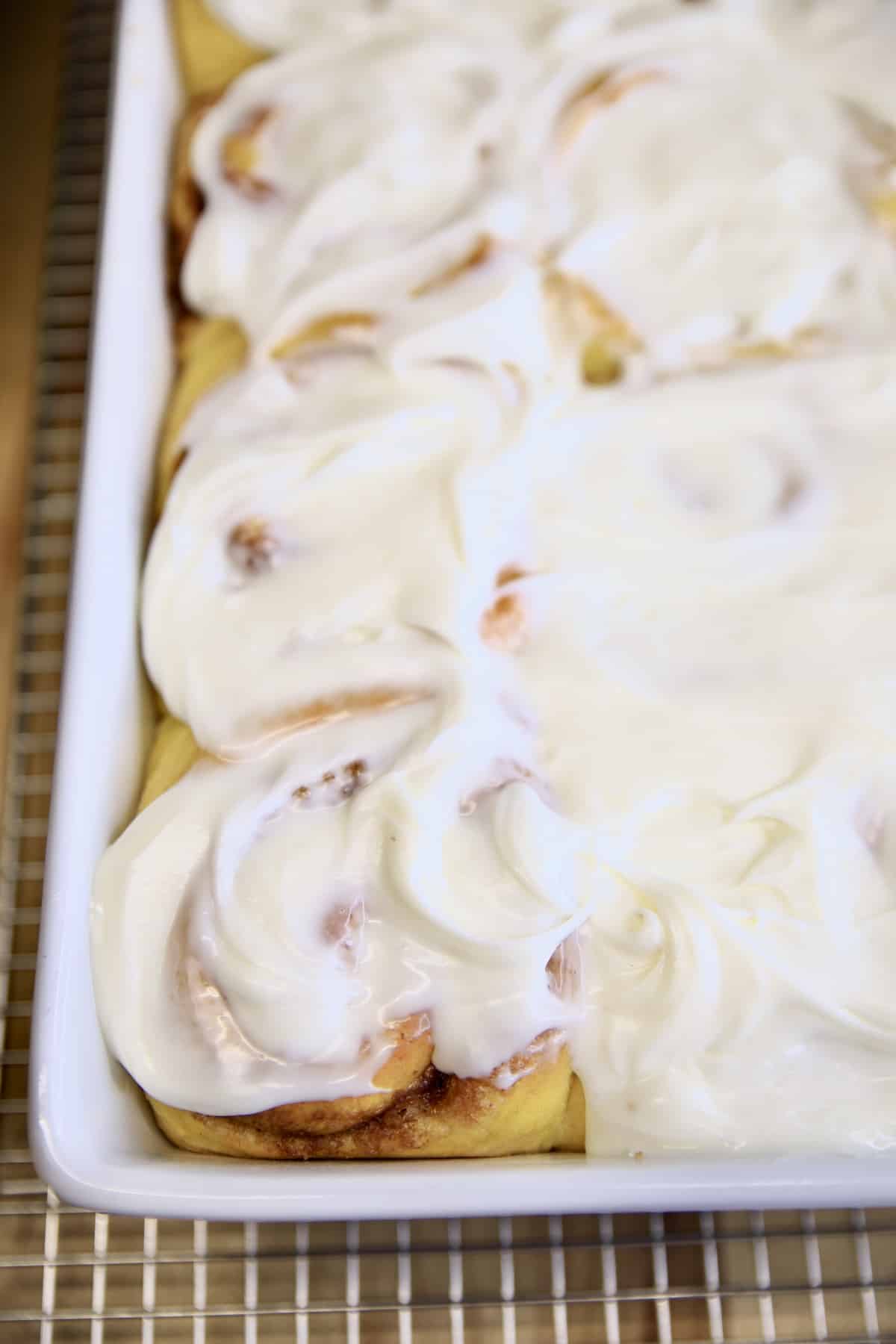 Pumpkin cinnamon rolls with cream cheese icing in a pan.