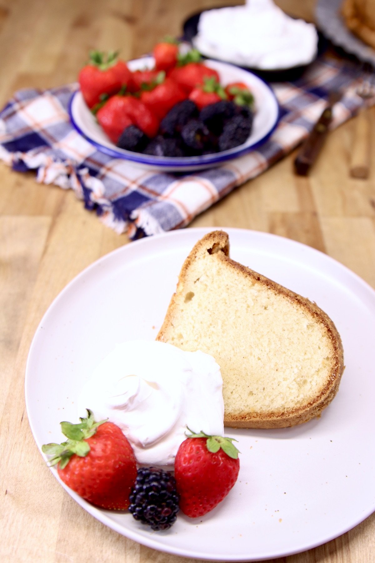 plate with sliced pound cake, whipped cream, berries