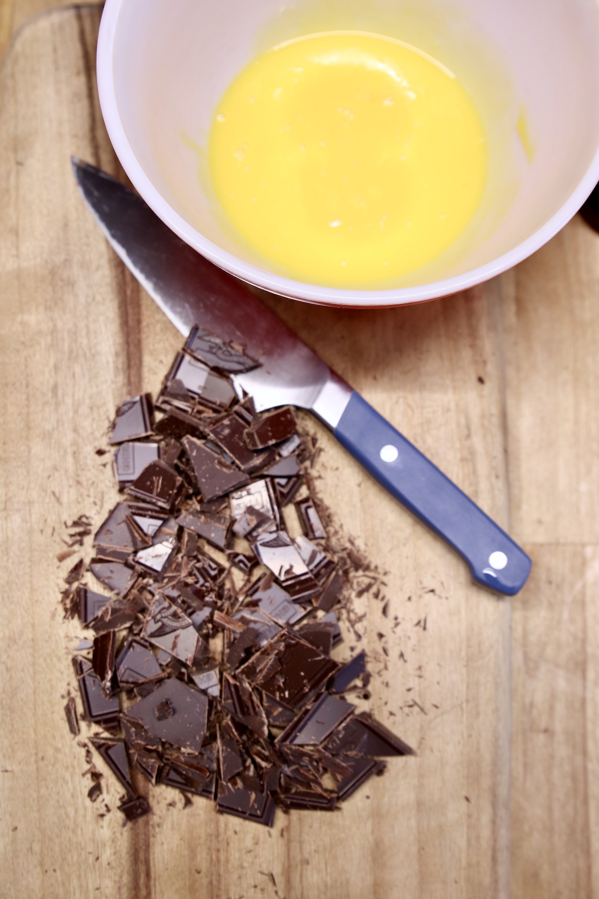 bowl of egg yolks, chopped chocolate with knife