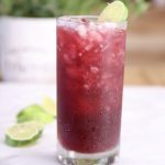 Pomegranate Margarita in a tall glass with lime wheel