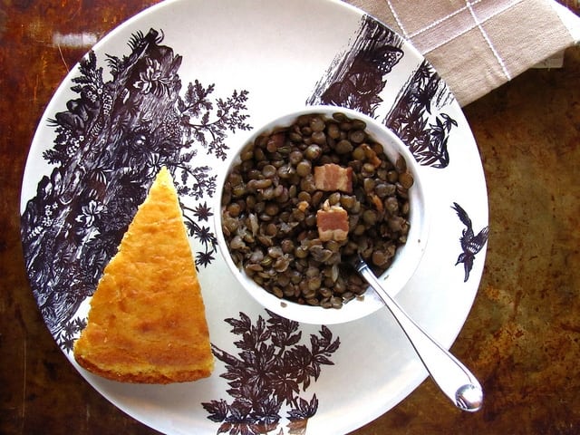 lentils in bowl with spoon and cornbread slice