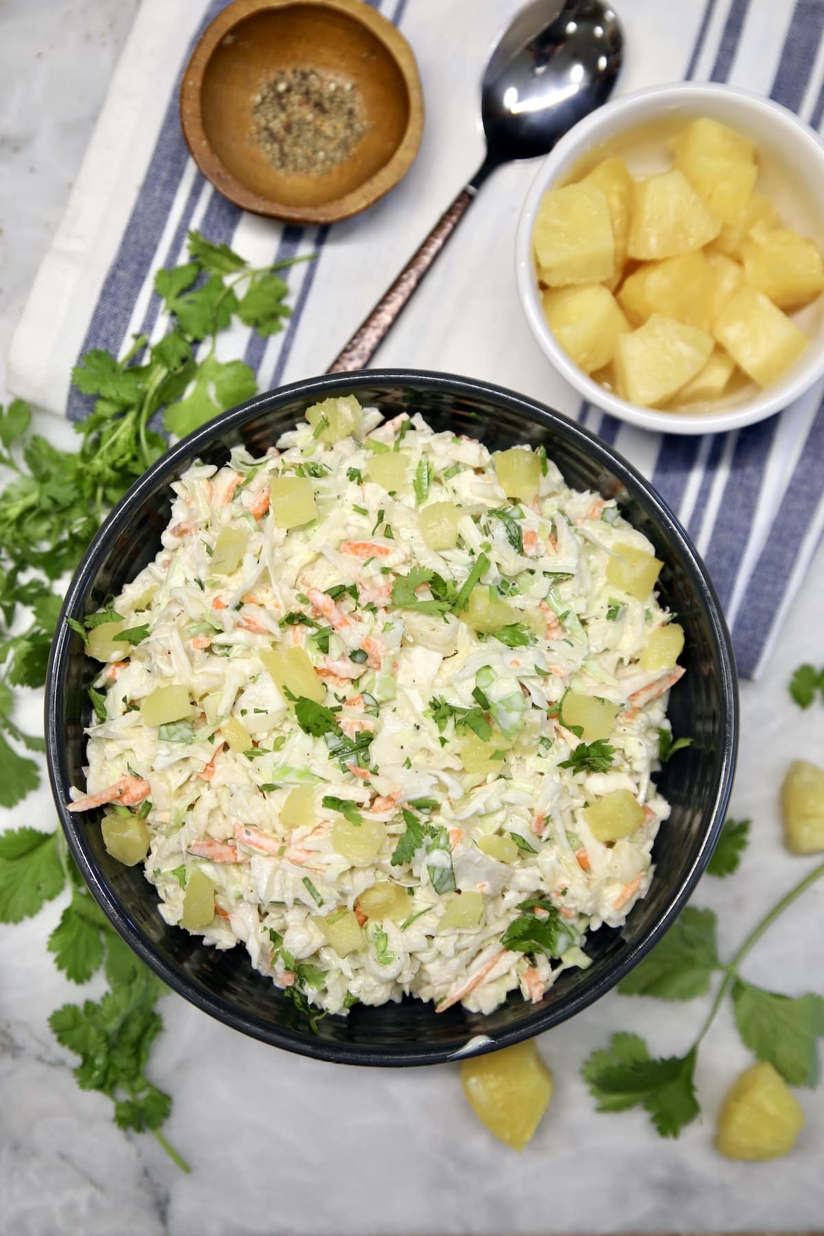 Bowl of pineapple coleslaw, small bowl of pineapple, cilantro.