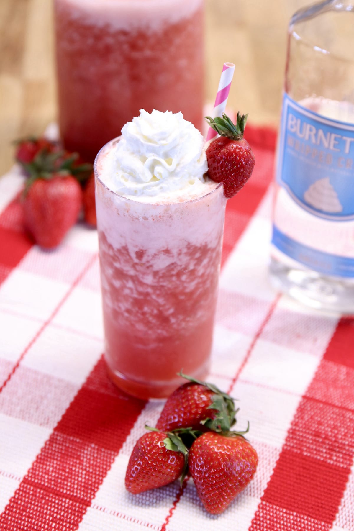 Strawberry cocktail with whipped cream garnish.
