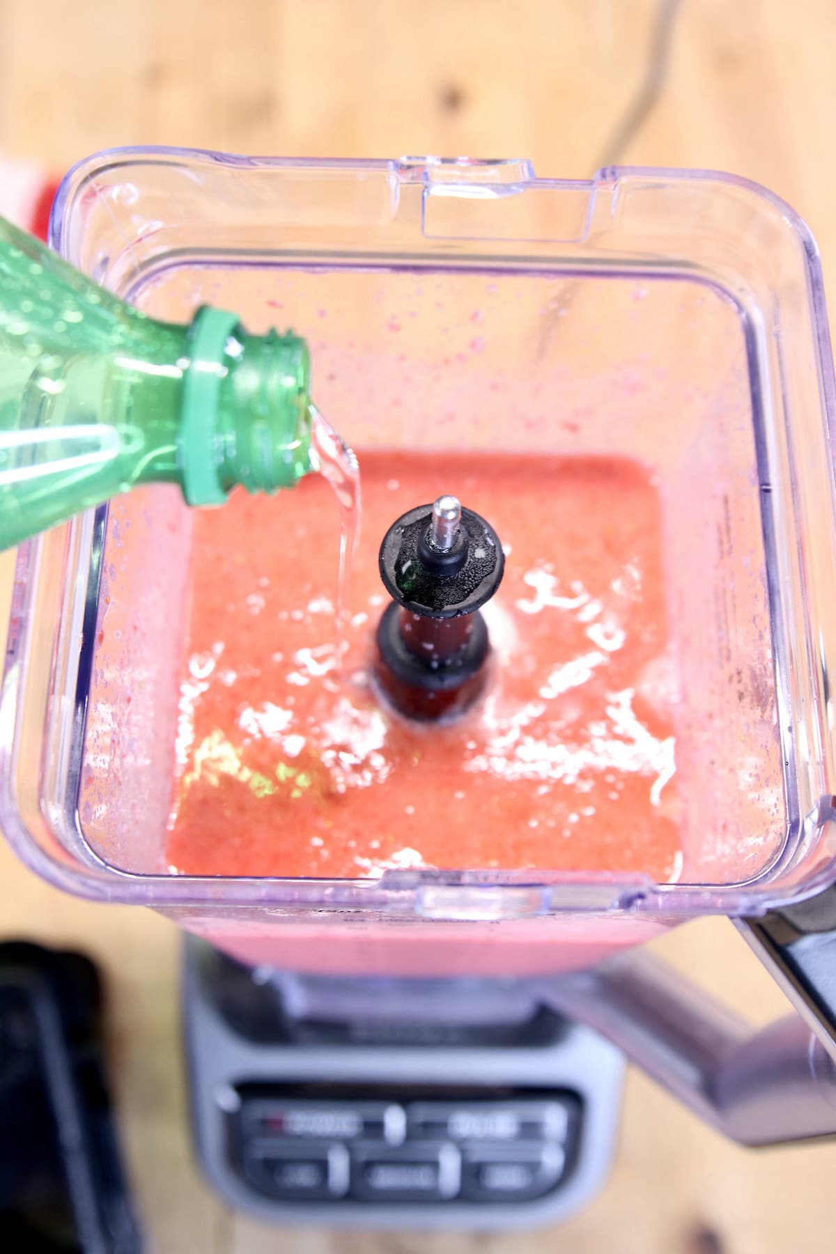 pouring sprite into blender with blended strawberries.