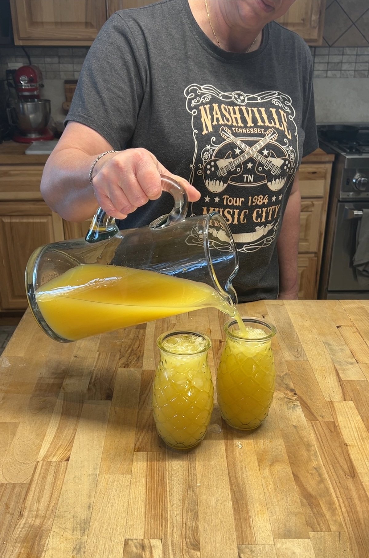 Filling tiki glasses with pineapple margaritas.