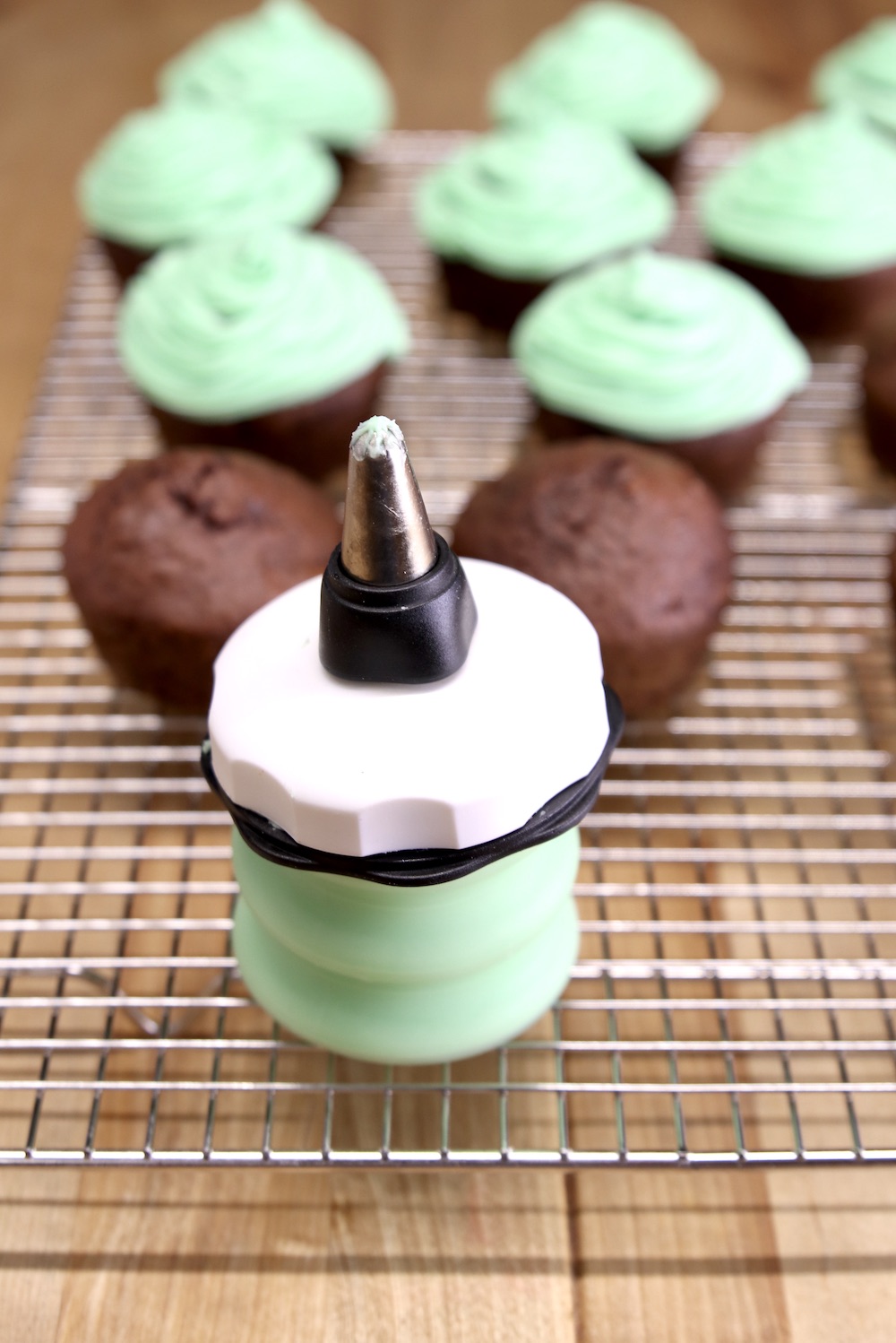 oxo decorator bottle for icing cupcakes, cupcakes in background