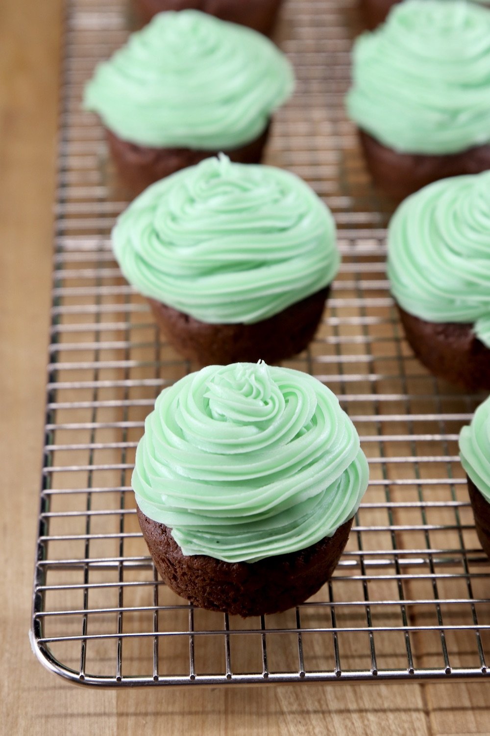 chocolate cupcakes with green mint icing on a wire rack