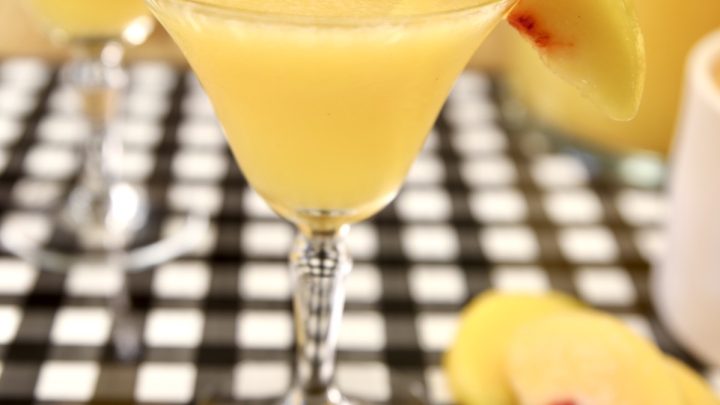 Peach moscato punch in a glass with peach slice.