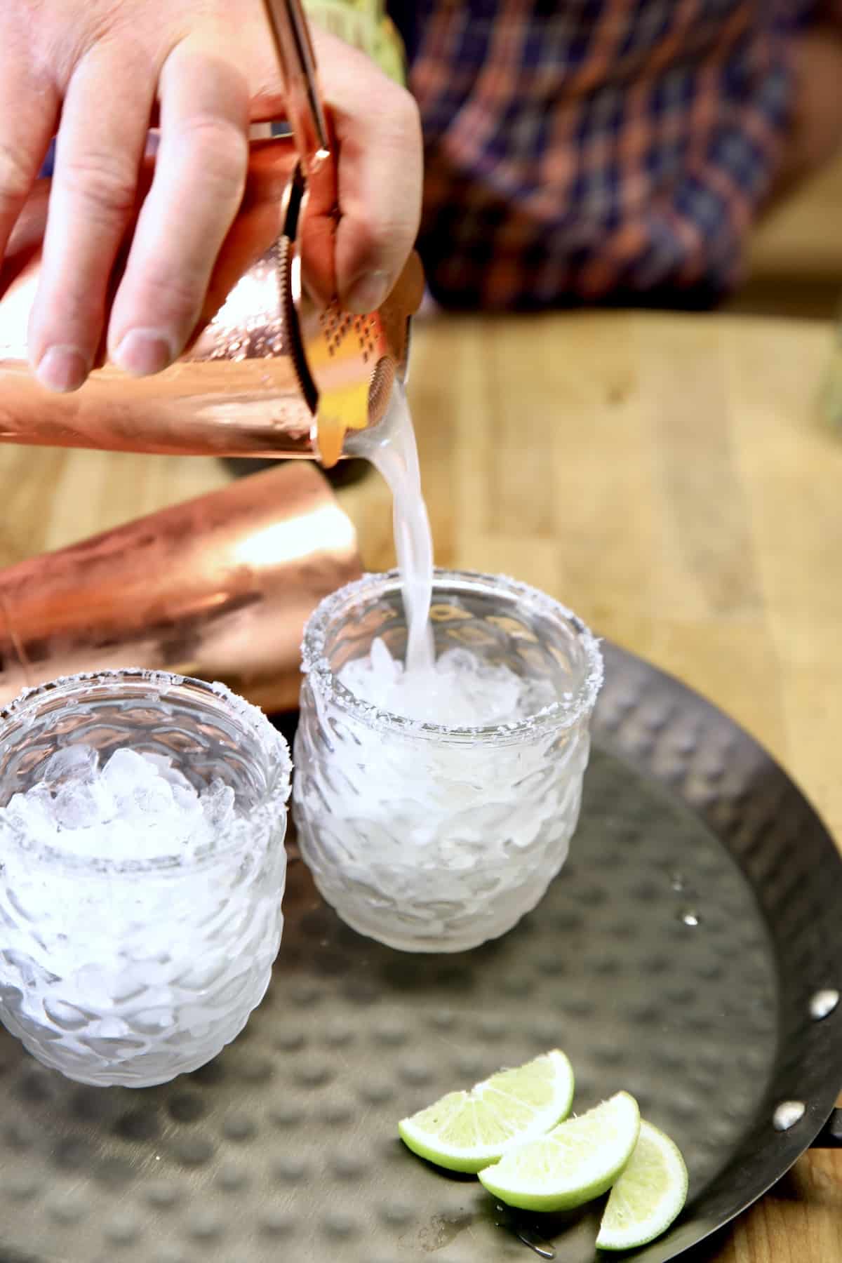 Pouring Margaritas into glasses with crushed ice.