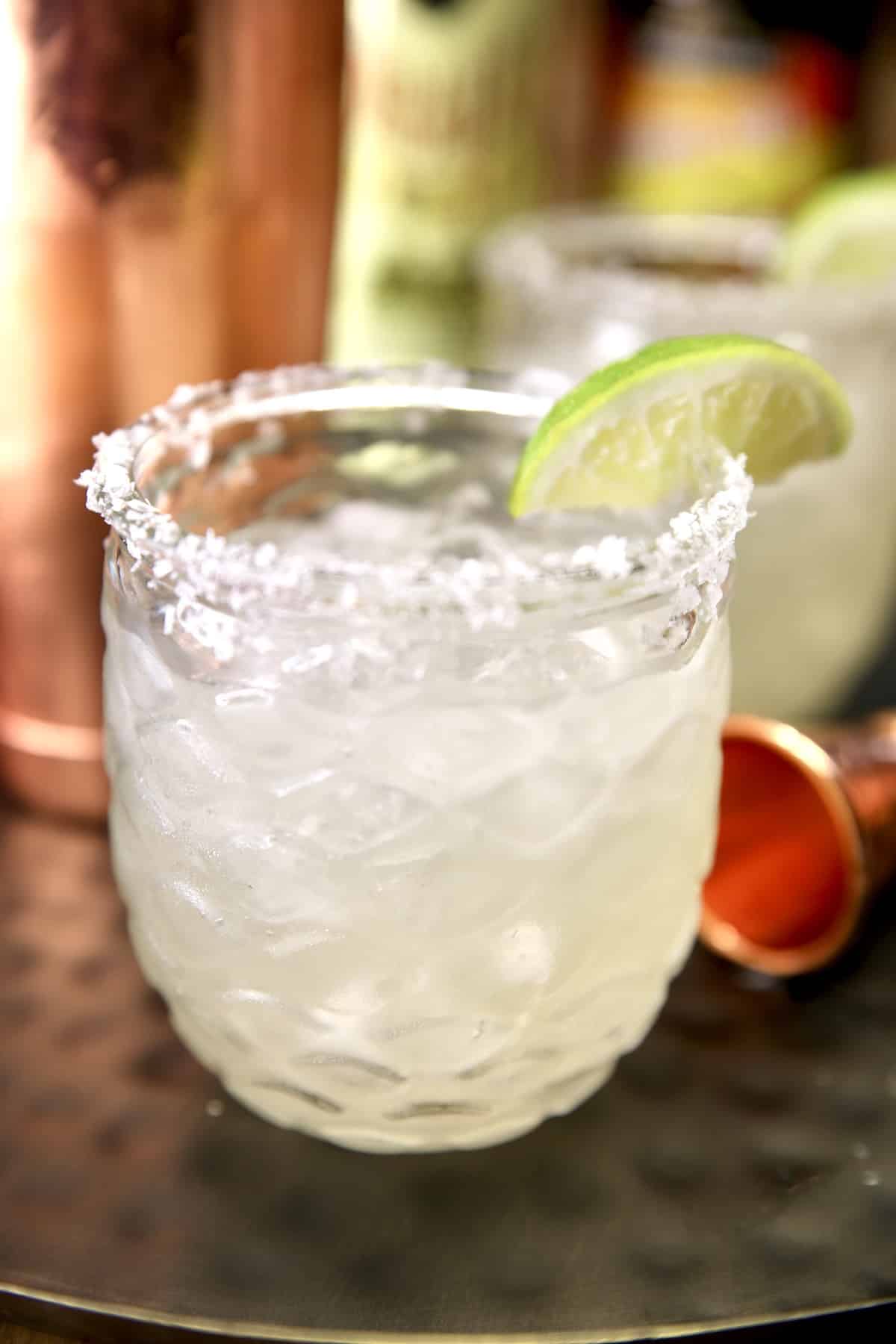 Margarita in a glass with salted rim and lime slice.