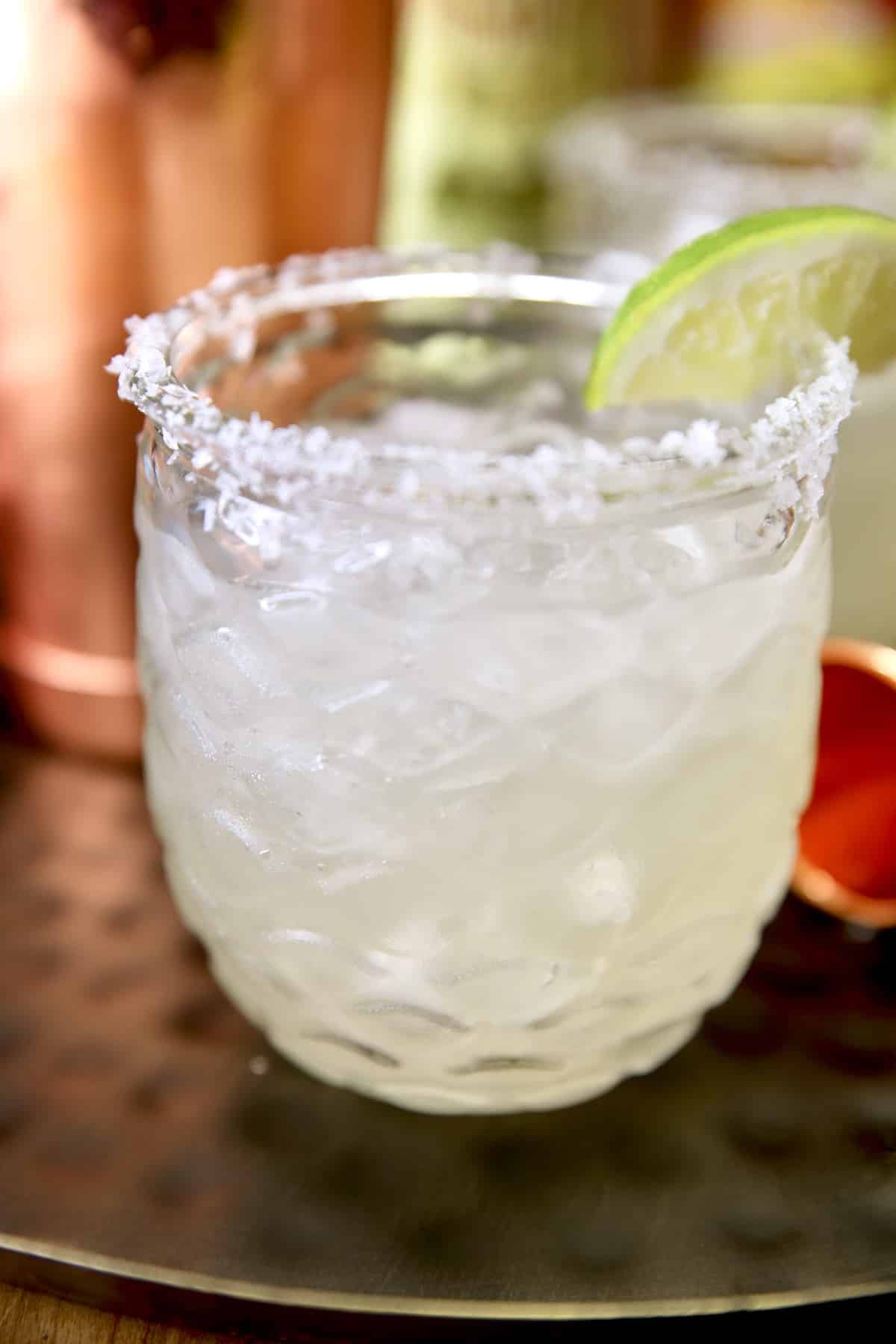 Margarita in a glass with slice of lime and salted rim.
