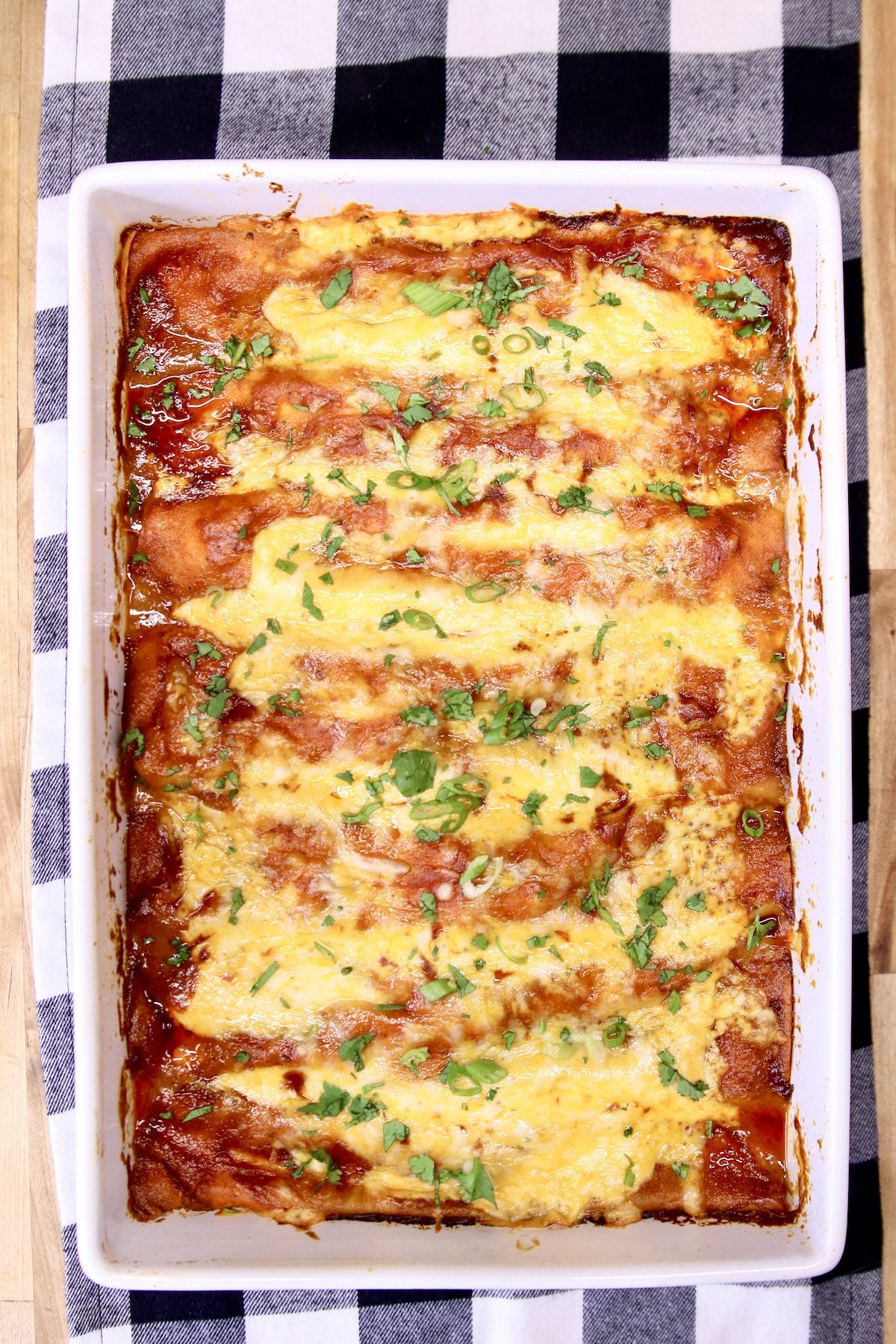 enchiladas in a pan with cilantro and green onion garnish