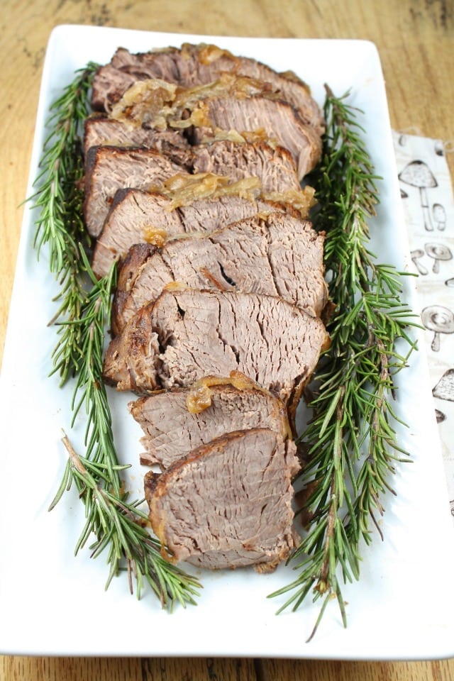 Sliced Pot Roast on a white platter, garnished with fresh rosemary