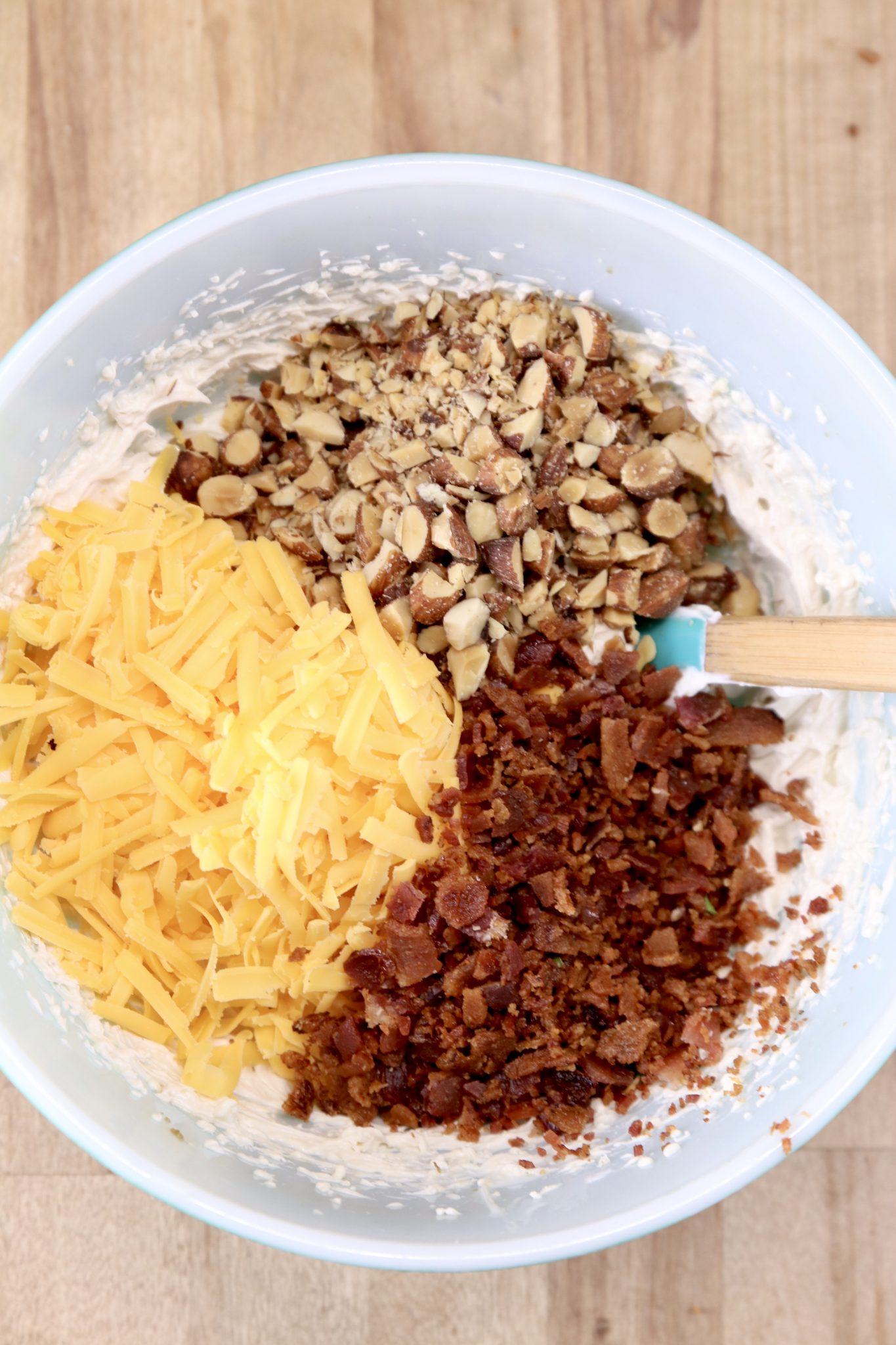 Bowl with crumbled bacon, shredded cheese and chopped almonds