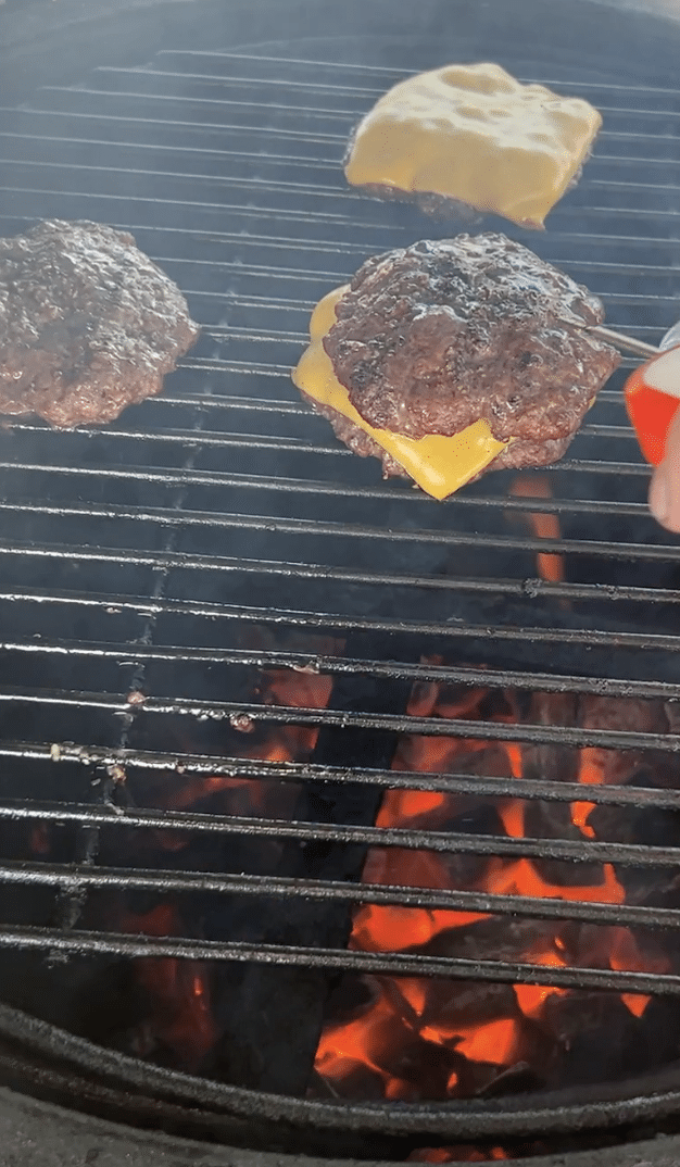 Making double cheeseburgers on a grill.