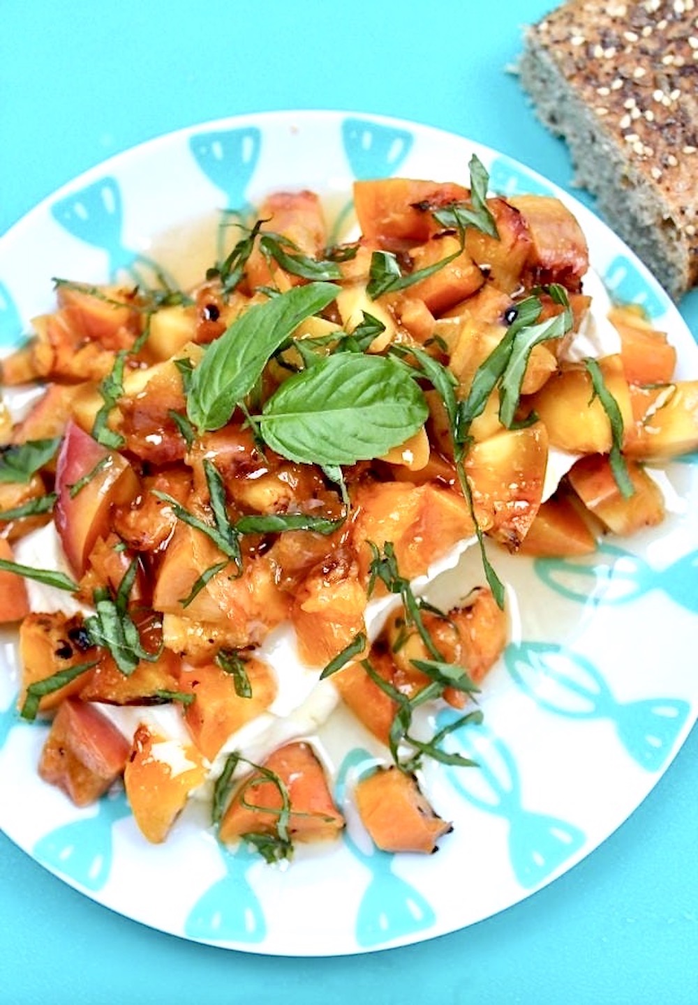 Grilled peach appetizer on a plate with basil