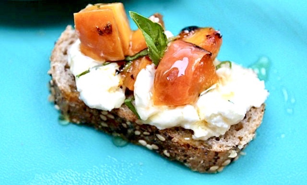 slice of toasted bread with cream cheese, peaches, basil and honey