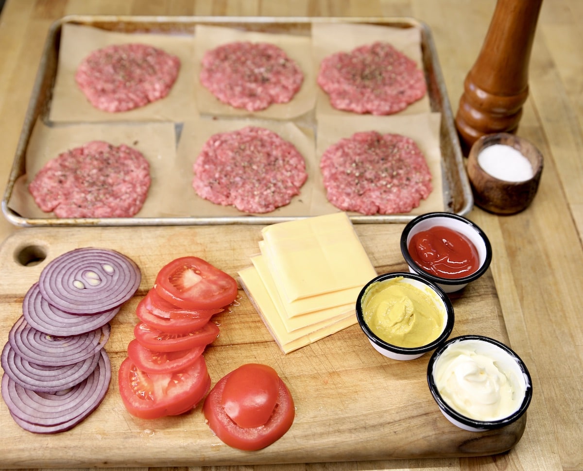 Burger patties, onion slices, tomato slices, cheese, condiments.
