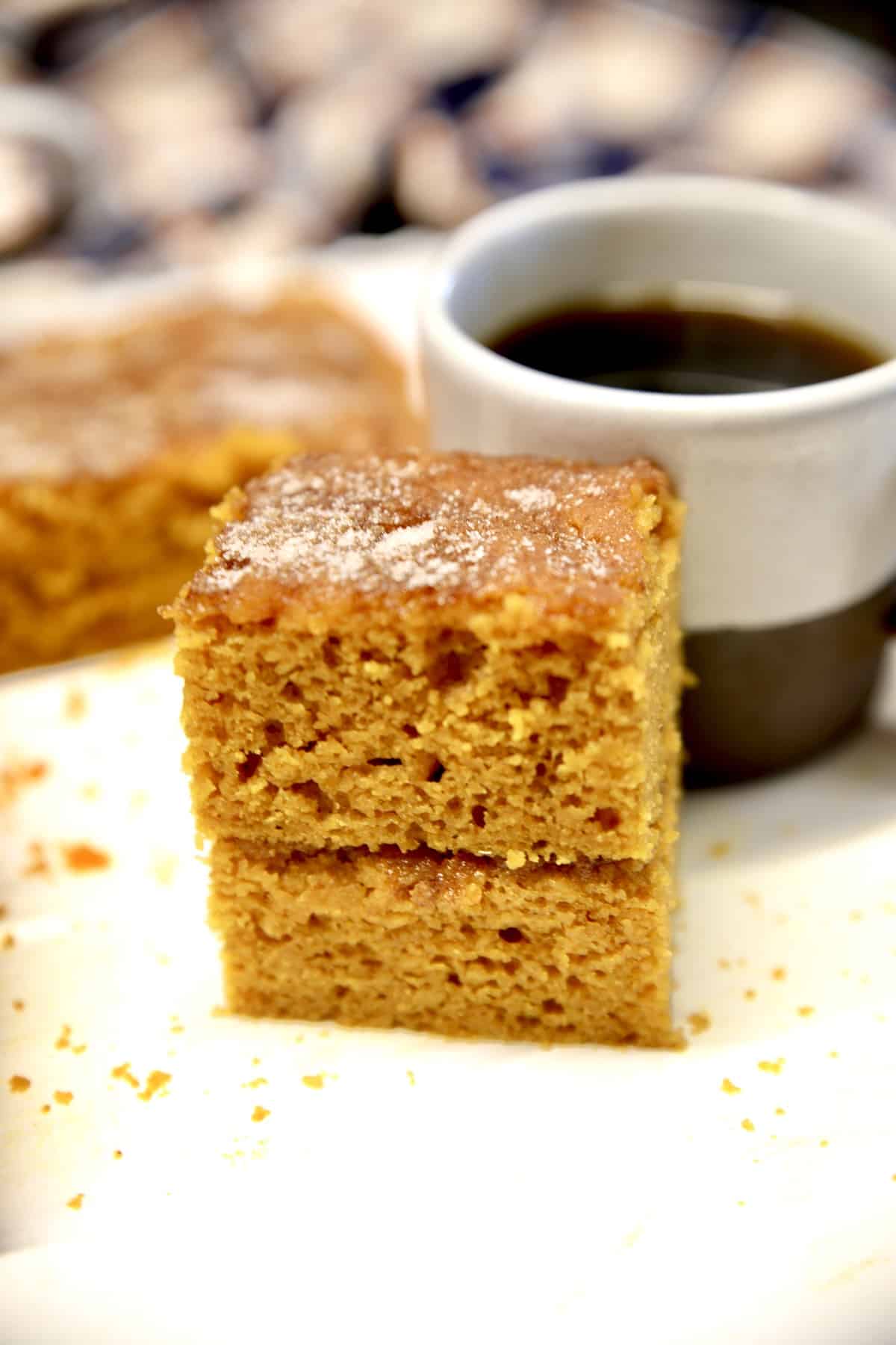 Pumpkin cake stacked in front of a coffee cup.