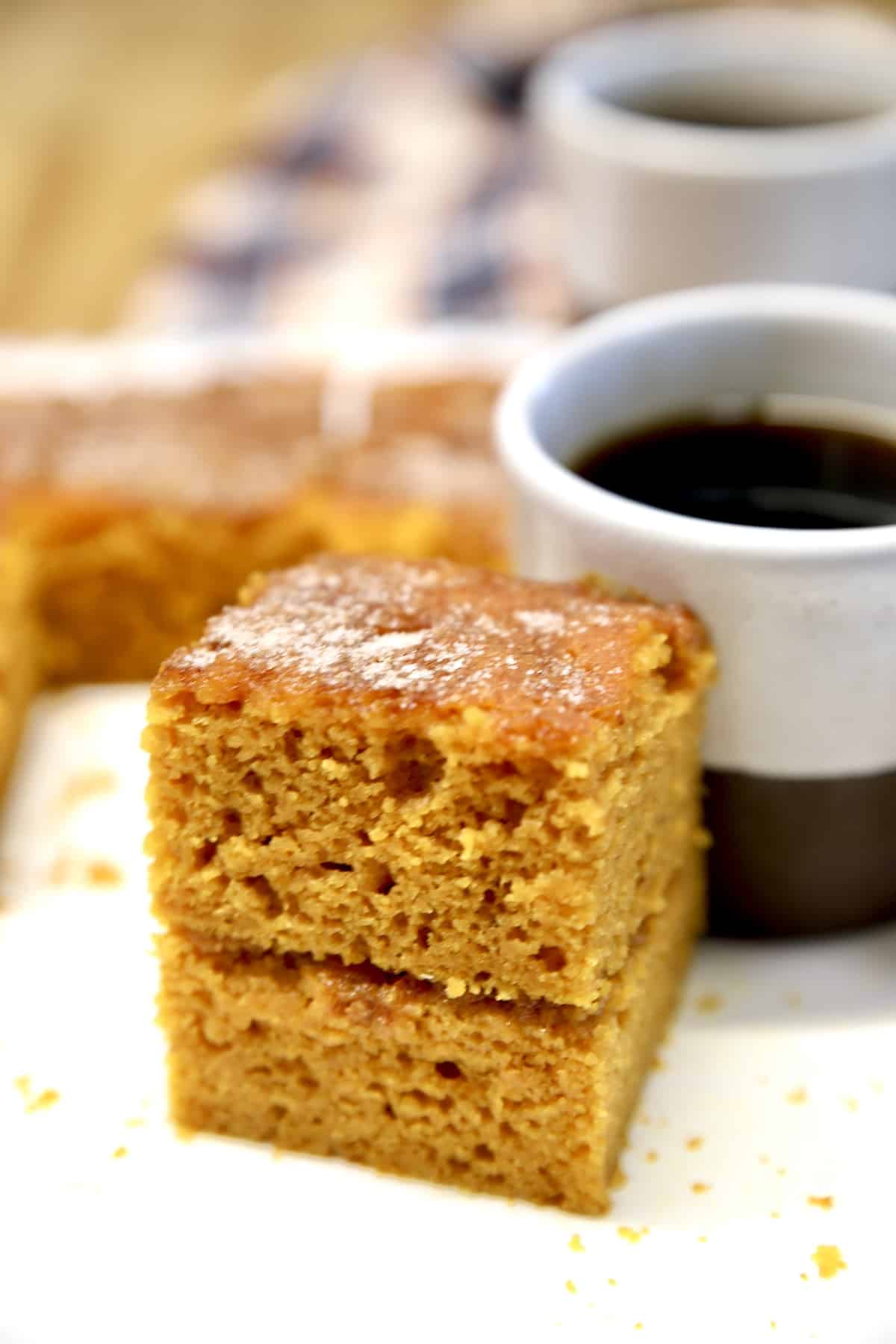 Pumpkin snack cake stacked beside coffee cup.