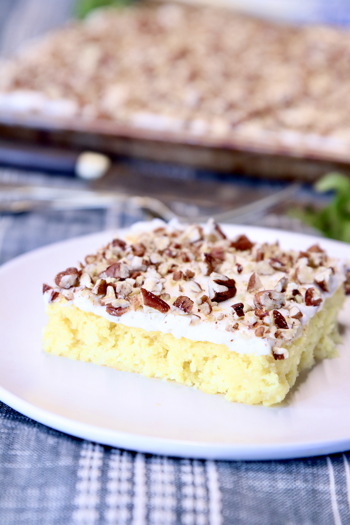 slice of pineapple sheet cake with icing and pecans