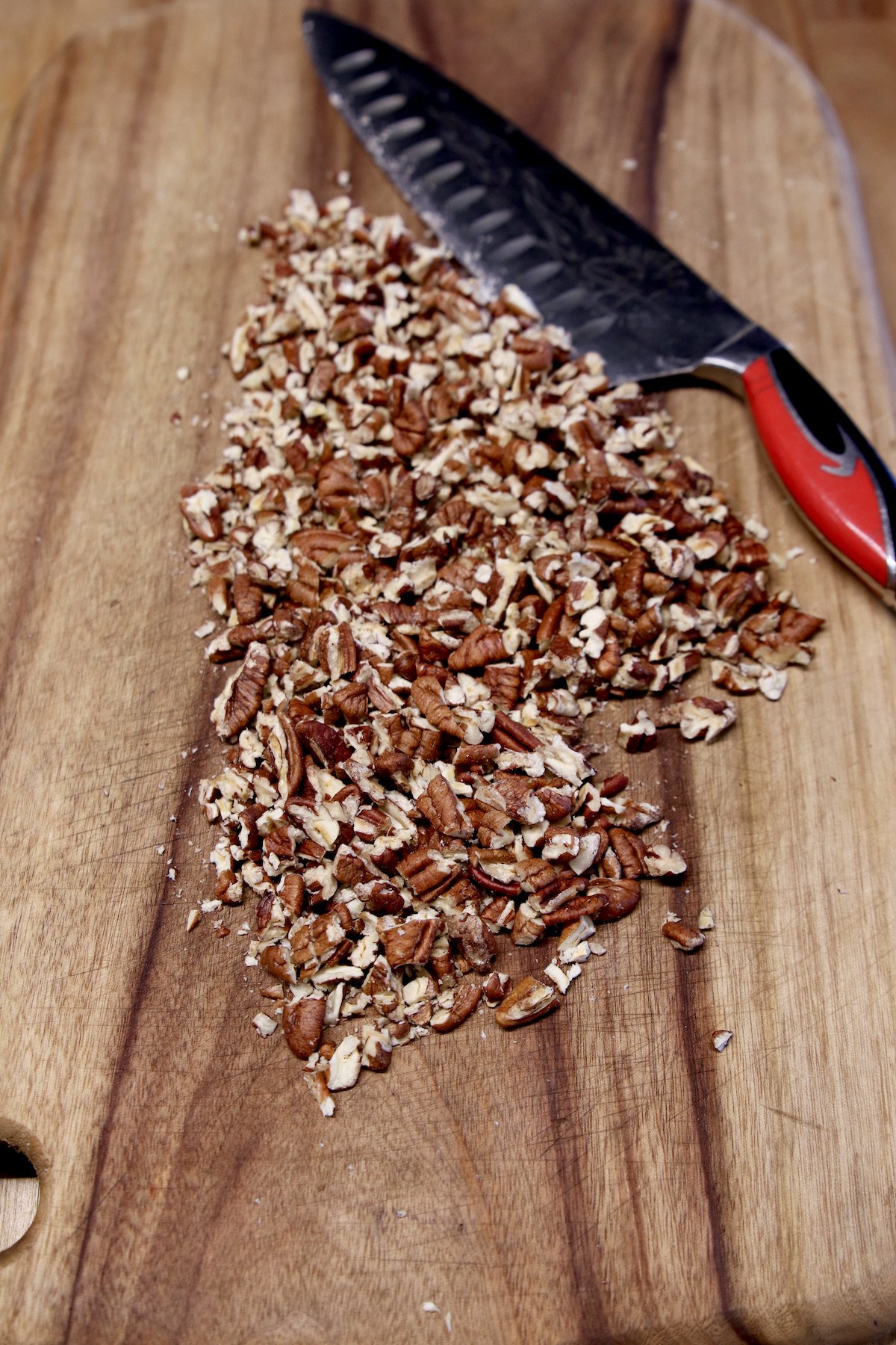 chopped pecans on a cutting board with a knife