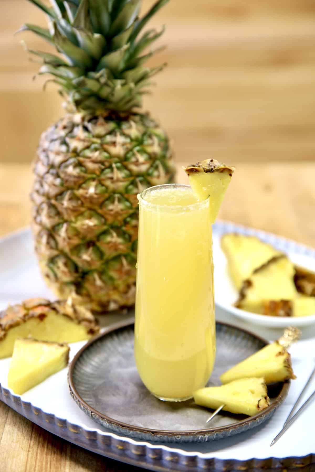 Pineapple mimosa with whole pineapple on a tray.