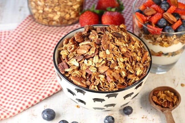Bowl of easy homemade granola with fresh strawberries and blueberries in the background
