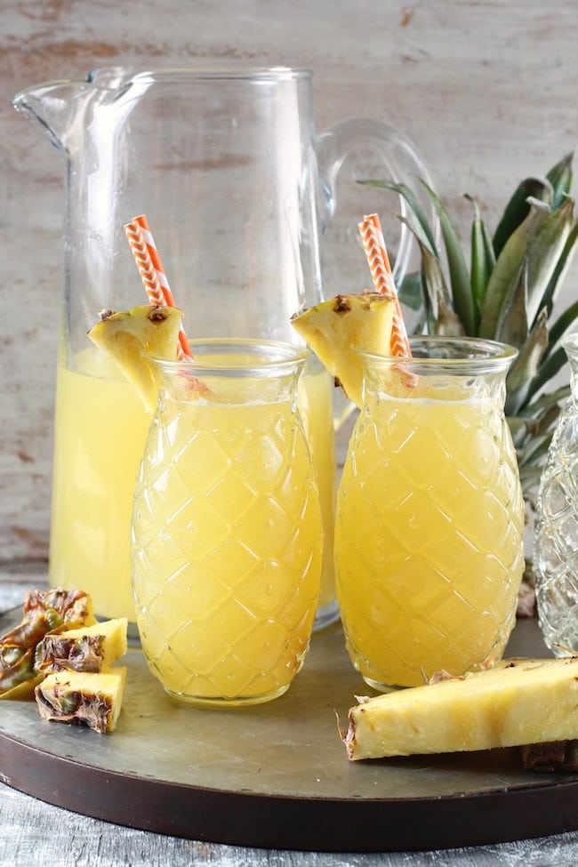 Glass Pitcher and Pineapple Shaped Glasses filled with Easy Pineapple Wine Punch with pineapple top and pineapple wedges