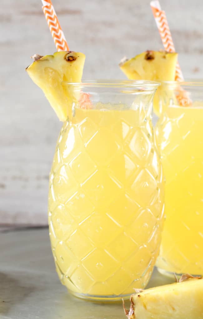 Easy Pineapple Wine Punch in Pineapple- shaped glasses garnished with a pineapple wedge