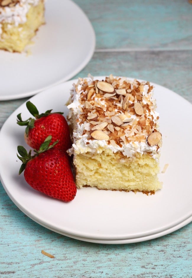 Slice of coconut cream cake, 2 strawberries on a white plate