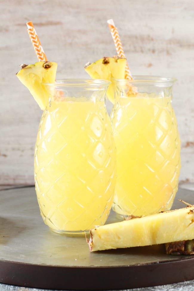 Pineapple Glasses filled with Easy Pineapple Wine Punch garnished with straws and pineapple wedges 