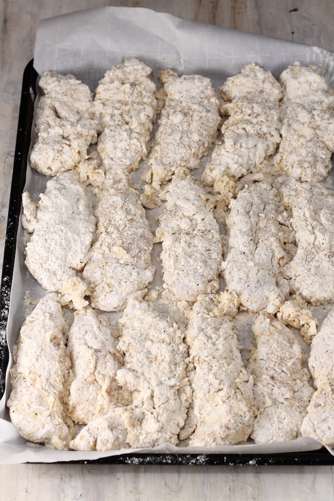 Battered Chicken Tenders on parchment paper ready for the fryer