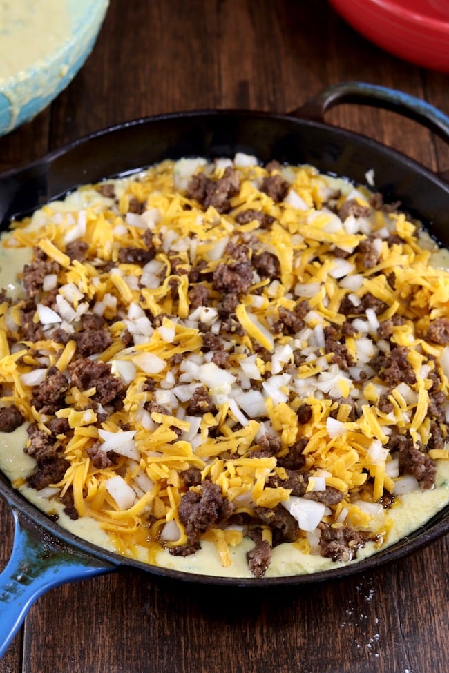Cooked ground beef, onion, and cheese layer for Mexican Cornbread in a cast iron skillet